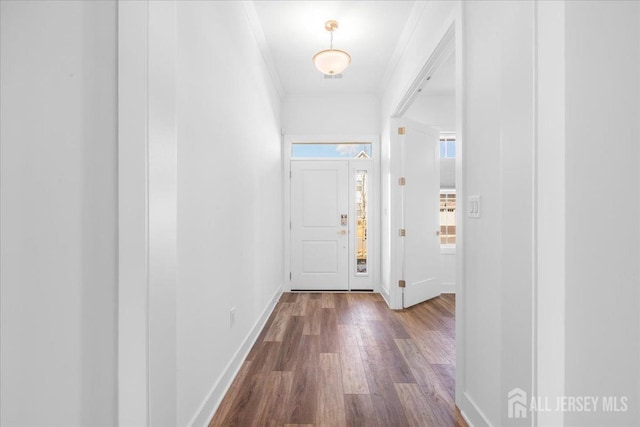 hall featuring dark wood finished floors, baseboards, and ornamental molding