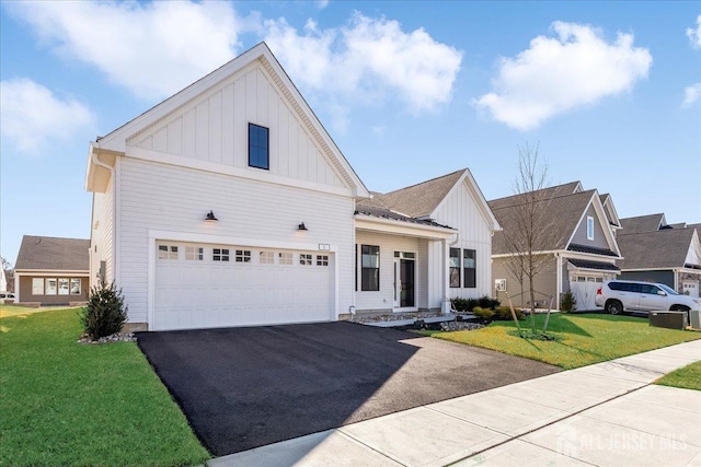 modern farmhouse with board and batten siding, an attached garage, driveway, and a front lawn