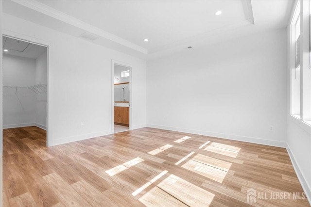 interior space with a raised ceiling, light wood-style flooring, recessed lighting, and baseboards