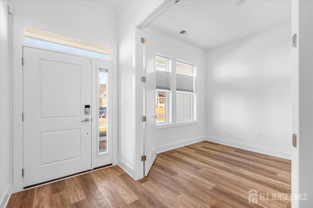 foyer entrance with baseboards, wood finished floors, and visible vents