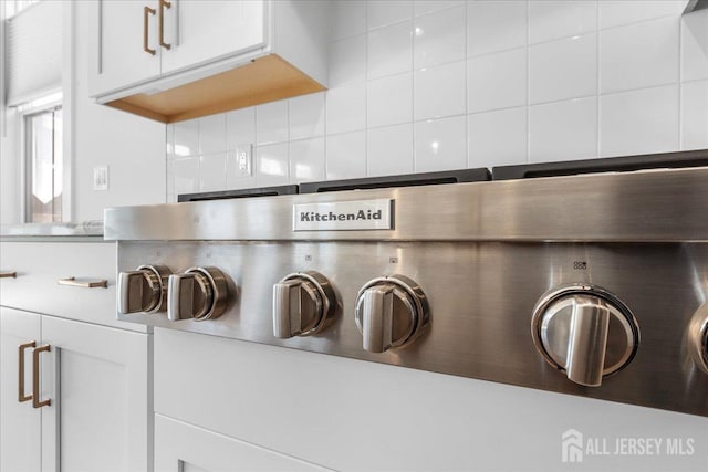 details with decorative backsplash, light countertops, and white cabinetry