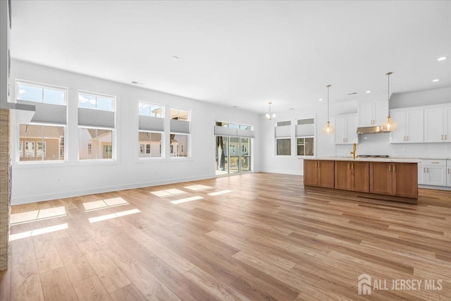 unfurnished living room featuring recessed lighting, baseboards, and light wood-style floors