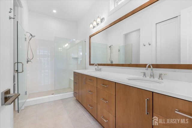 bathroom with tile patterned flooring, a sink, double vanity, and a shower stall