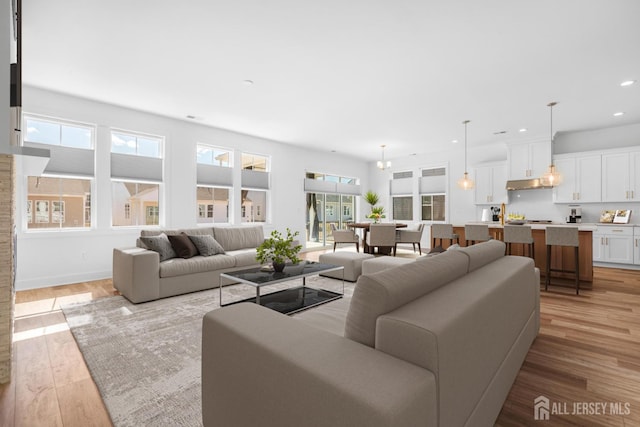 living area featuring recessed lighting, baseboards, and light wood-style floors