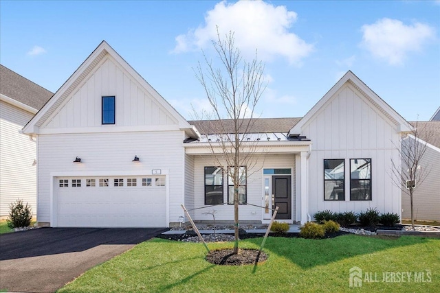 view of front of house with board and batten siding, a standing seam roof, driveway, and a front lawn