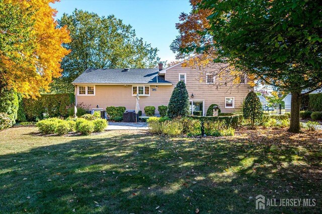 back of property with a lawn and a patio