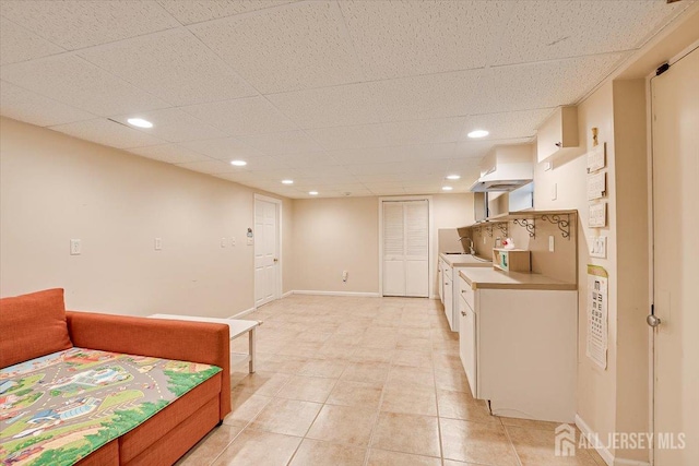 kitchen with white cabinetry, light tile patterned flooring, sink, and a drop ceiling