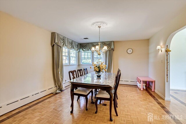 dining area with a notable chandelier, light parquet floors, and a baseboard radiator