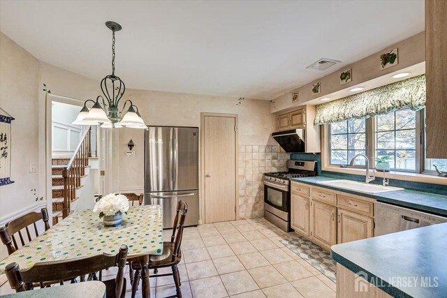 kitchen featuring light brown cabinetry, sink, ventilation hood, hanging light fixtures, and appliances with stainless steel finishes