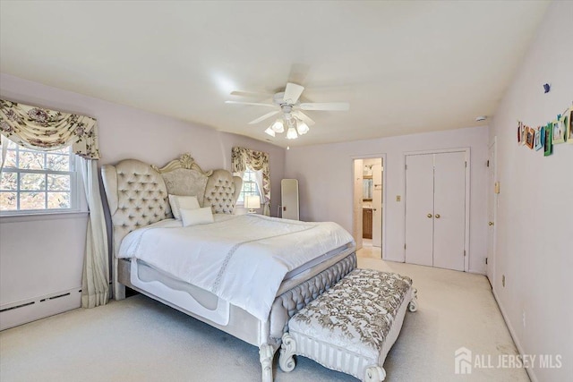 bedroom featuring light carpet, ensuite bath, a baseboard radiator, and ceiling fan