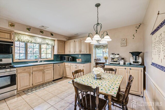 kitchen featuring decorative light fixtures, a notable chandelier, sink, stainless steel appliances, and light tile patterned floors