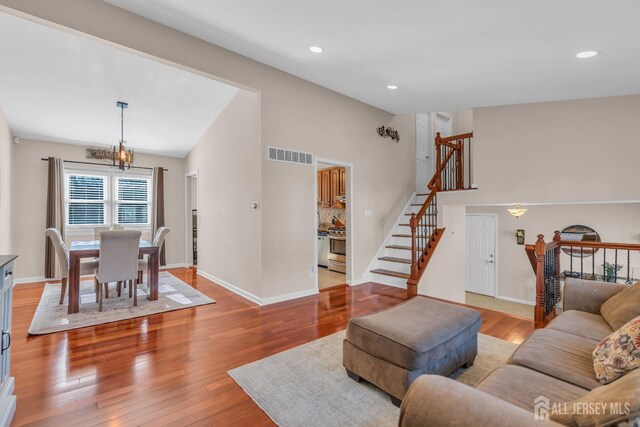 living room with light hardwood / wood-style flooring, high vaulted ceiling, and a chandelier