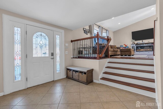 foyer featuring vaulted ceiling and light tile patterned flooring