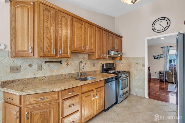 kitchen with light stone counters, appliances with stainless steel finishes, sink, and light tile patterned floors