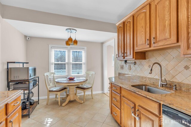 kitchen with tasteful backsplash, sink, light tile patterned floors, stainless steel appliances, and light stone countertops