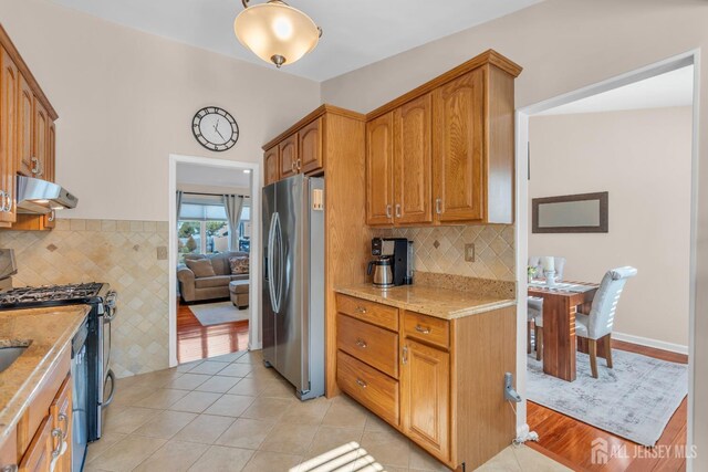 kitchen with light stone counters, appliances with stainless steel finishes, and light tile patterned floors