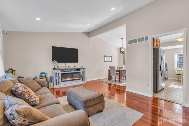 living room with vaulted ceiling and light wood-type flooring