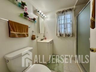 bathroom with toilet, an enclosed shower, and vanity