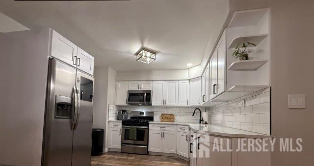 13 Heritage Ln, Fords, NJ 08863 - kitchen featuring stainless steel appliances, open shelves, light countertops, white cabinetry, and backsplash