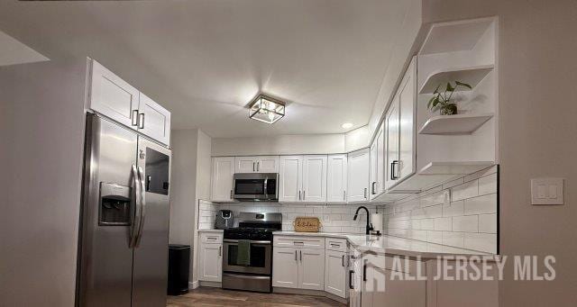 13 Heritage Ln, Fords, NJ 08863 - kitchen with appliances with stainless steel finishes, open shelves, light countertops, white cabinetry, and decorative backsplash