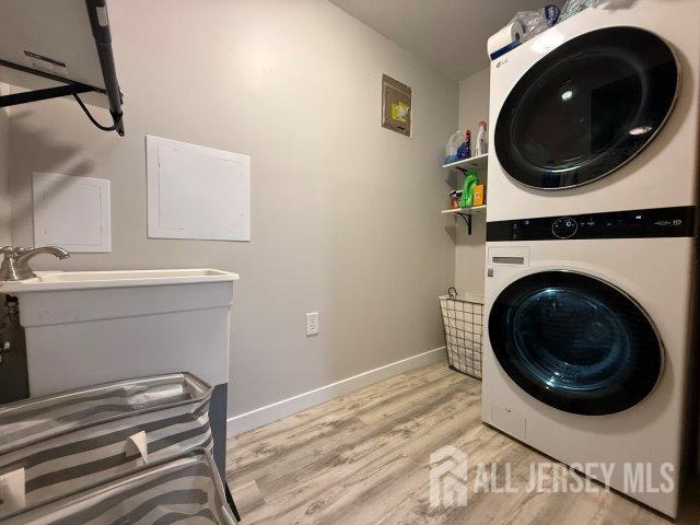 13 Heritage Ln, Fords, NJ 08863 - washroom featuring stacked washer and clothes dryer, light wood finished floors, and baseboards