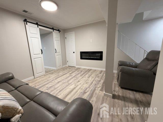 13 Heritage Ln, Fords, NJ 08863 - living room with light wood-type flooring, a barn door, baseboards, and a glass covered fireplace