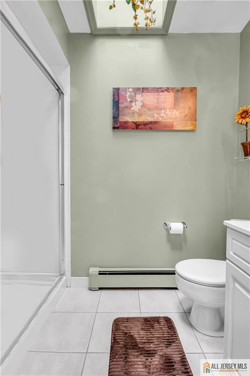 706 Wood Ave, North Brunswick, NJ 08902 - bathroom with a baseboard heating unit, tile patterned floors, a shower stall, and vanity