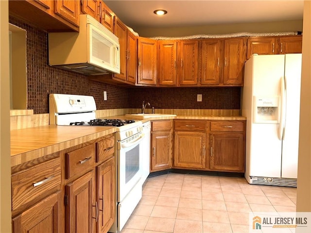 kitchen with sink, white appliances, tasteful backsplash, and light tile patterned floors