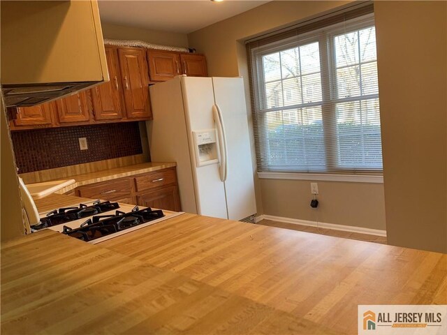 kitchen with gas stovetop, backsplash, and white fridge with ice dispenser