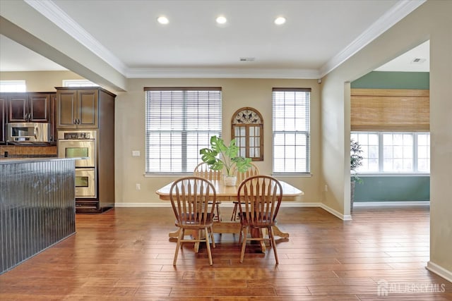 dining area with baseboards, wood finished floors, healthy amount of natural light, crown molding, and recessed lighting