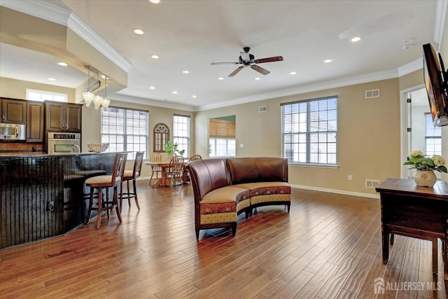living room featuring baseboards, a ceiling fan, recessed lighting, wood finished floors, and crown molding