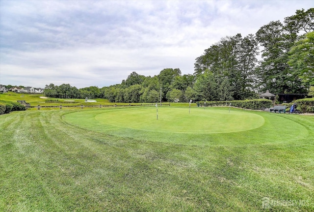 surrounding community featuring golf course view, a putting area, a lawn, and view of scattered trees