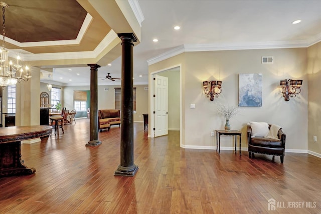 foyer entrance with decorative columns, ornamental molding, wood-type flooring, baseboards, and ceiling fan