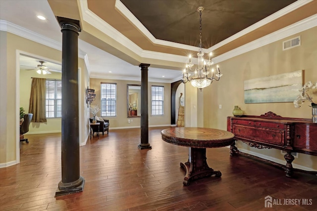 dining area featuring decorative columns, a raised ceiling, baseboards, ornamental molding, and wood finished floors