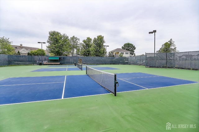view of tennis court with community basketball court and fence