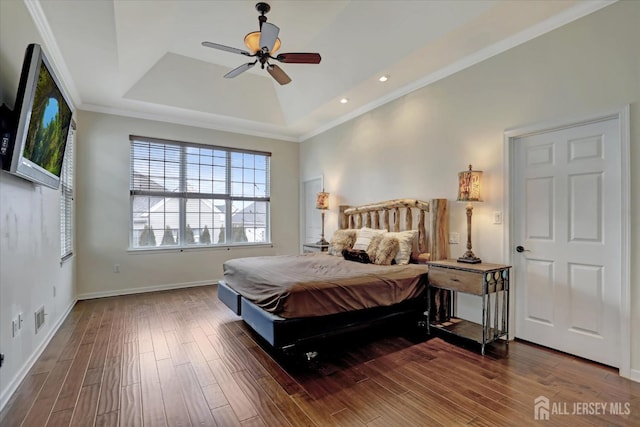 bedroom featuring a tray ceiling, baseboards, wood finished floors, ornamental molding, and ceiling fan