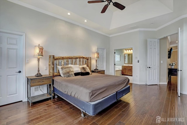 bedroom with a tray ceiling, wood finished floors, recessed lighting, crown molding, and ensuite bath