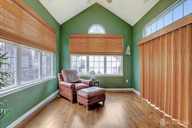 sitting room with baseboards, hardwood / wood-style flooring, a ceiling fan, and high vaulted ceiling