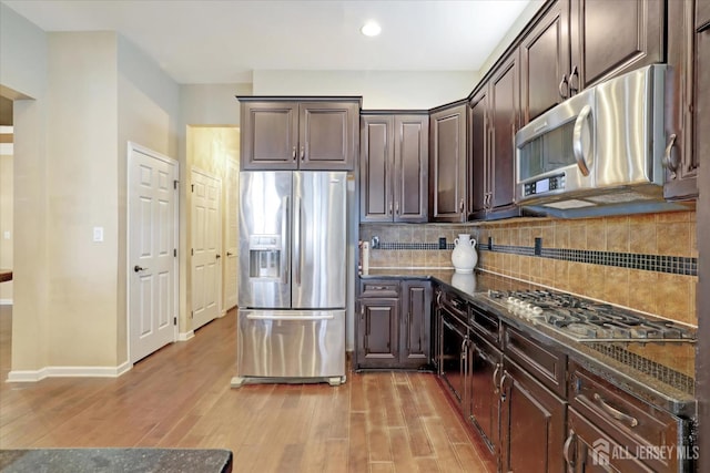 kitchen with appliances with stainless steel finishes, dark brown cabinets, tasteful backsplash, light wood-style floors, and recessed lighting