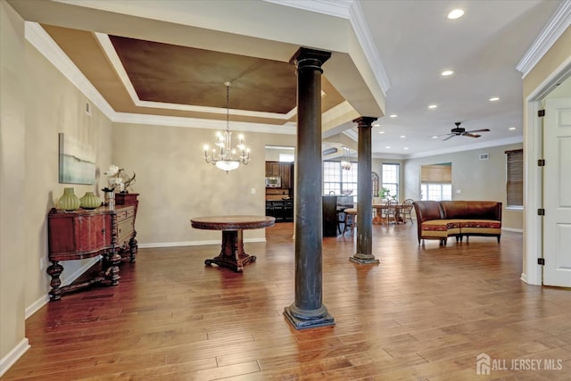 entrance foyer featuring ornate columns, ceiling fan, ornamental molding, wood finished floors, and baseboards