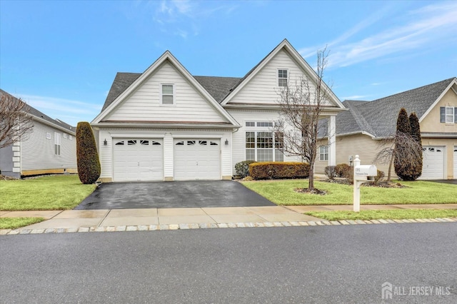 traditional-style house with a shingled roof, driveway, and a front lawn