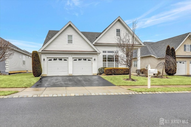 traditional-style home with driveway, a front lawn, a garage, and roof with shingles