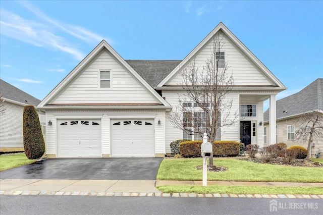 traditional home with driveway, an attached garage, and a front yard