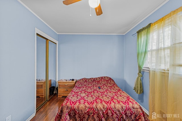 bedroom featuring crown molding, dark wood-style floors, a closet, and a ceiling fan