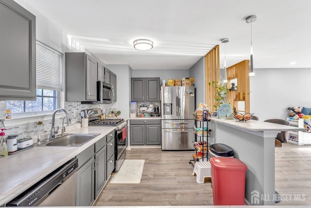 kitchen featuring stainless steel appliances, hanging light fixtures, sink, and gray cabinetry