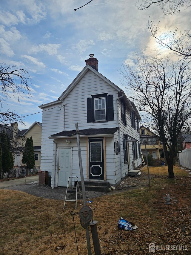 traditional home with a chimney and a front lawn