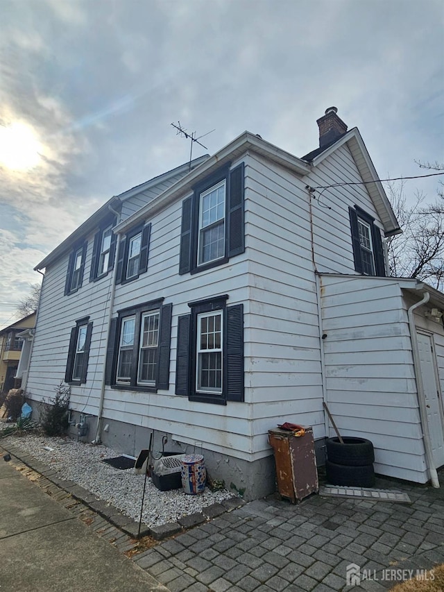 view of side of property featuring a patio area and a chimney