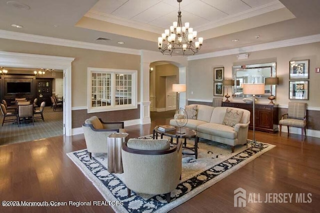 living room with a raised ceiling, an inviting chandelier, crown molding, and dark hardwood / wood-style floors