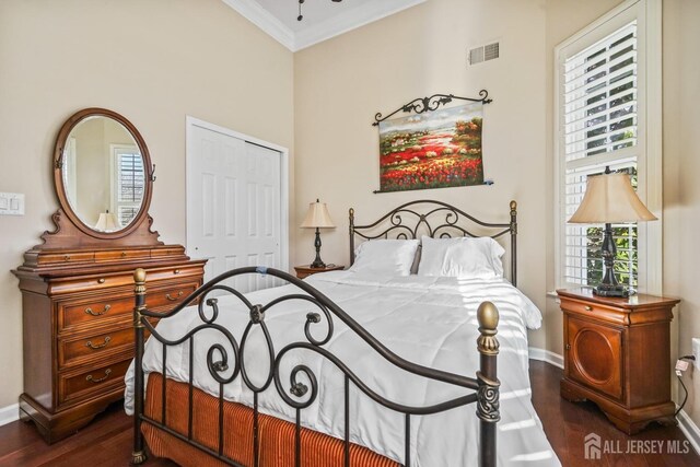 bedroom with a closet, crown molding, and dark hardwood / wood-style flooring