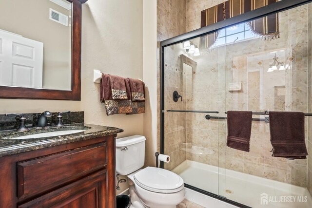 bathroom with a notable chandelier, walk in shower, vanity, and toilet